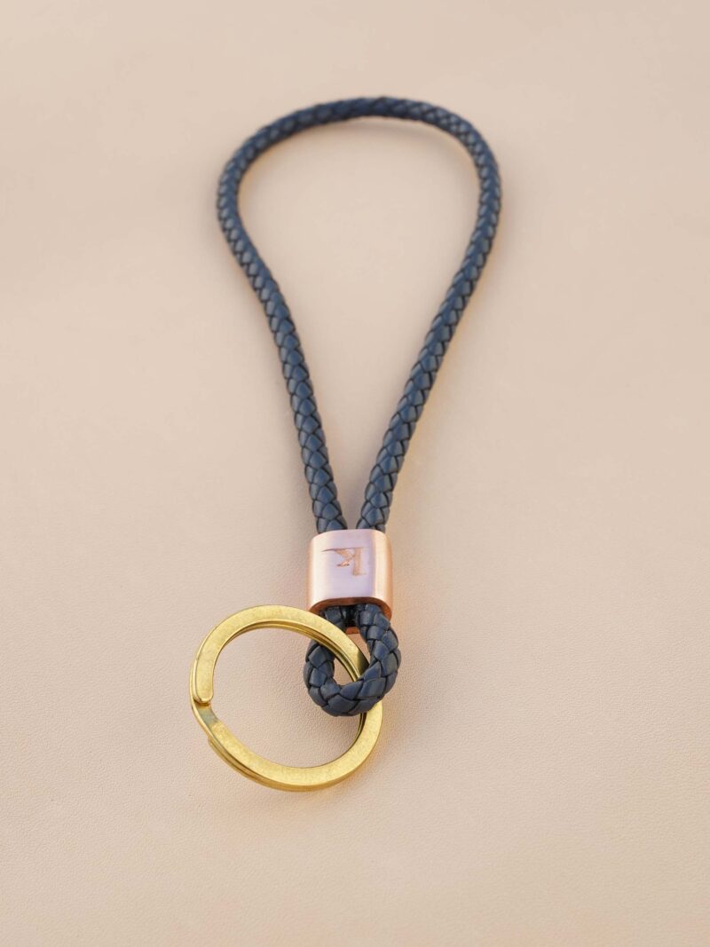 Handgemachter Schlüsselbändel von KikieKoch Procida, rund geflochten aus blauem Rindsleder, mit geprägter Kupferklemme und grossem Schlüsselring aus Messing.