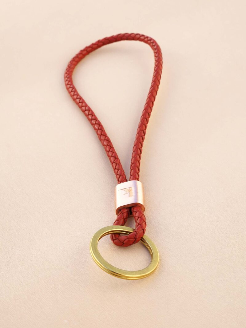 Handgemachter Schlüsselbändel von KikieKoch Procida, rund geflochten aus rotem Rindsleder, mit geprägter Kupferklemme und grossem Schlüsselring aus Messing.