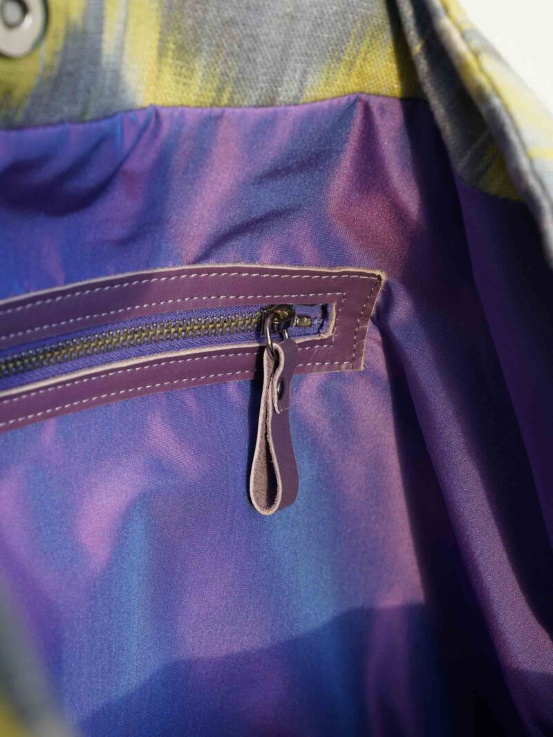 Innentasche mit Reissverschluss der handgemachten Schultertasche von KikieKoch Procida aus gelb-grau gezickzacktem Ikat Stoff. Boden und Träger aus violettem Rindsleder.