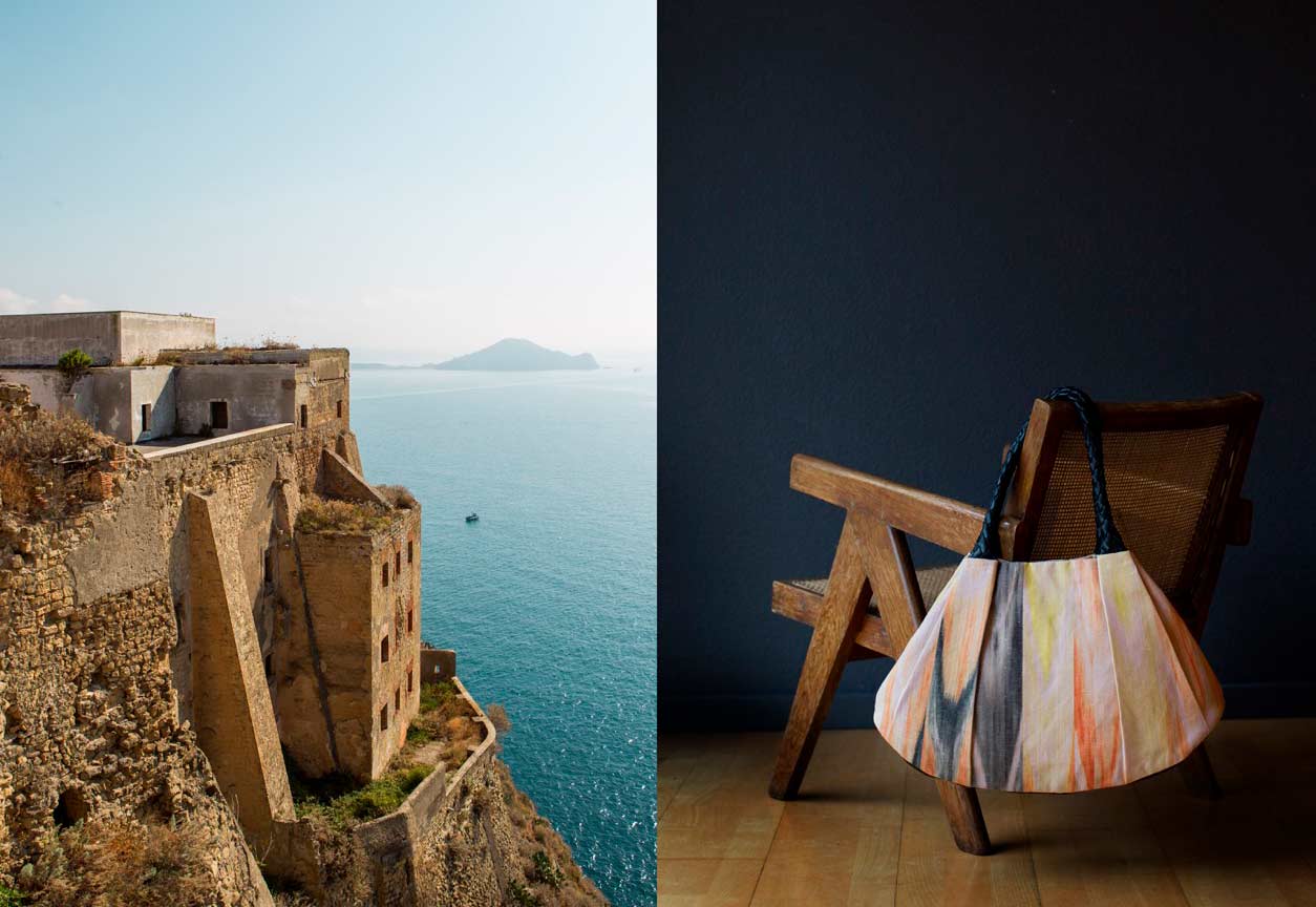 Links: Procida Terra Murata, schroffe Architektur, im Hintergrund weites Meer mit Sicht auf Capri. Rechts: KikieKoch Tasche aus mehrfarbigem Ikat Stoff mit rundgeflochten Trägern und Boden aus schwarzem Rindsleder. Die Tasche hängt an der Lehne eines Chandigarh Sessels.